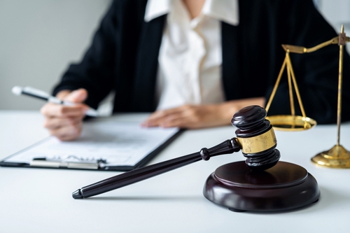 Lawyer reviewing document at desk beside laptop and eyeglasses
