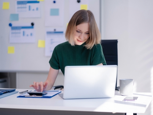 professional woman using calculator at desk with laptop and documents